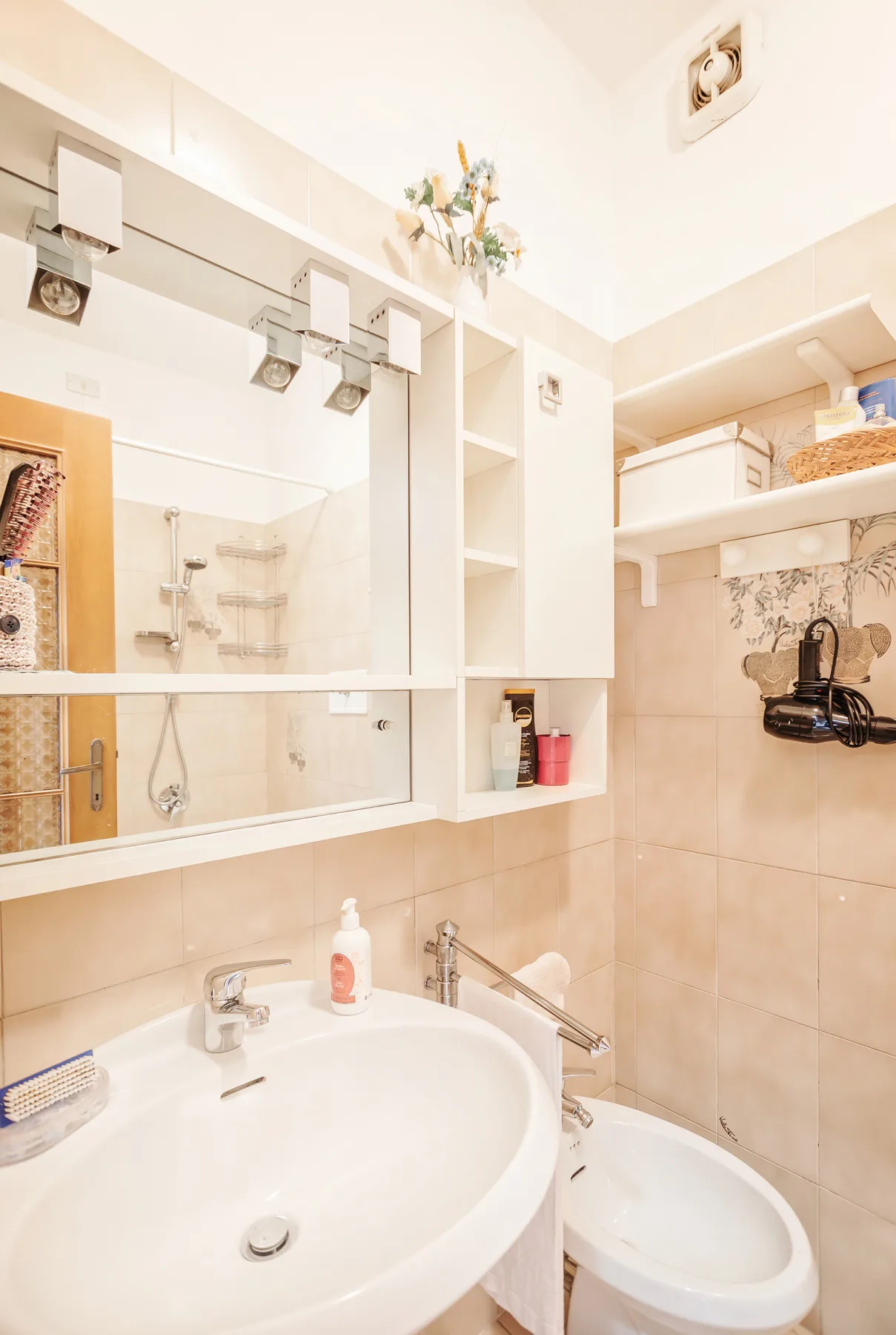 A bright bathroom with a sink, mirror, and bathtub.