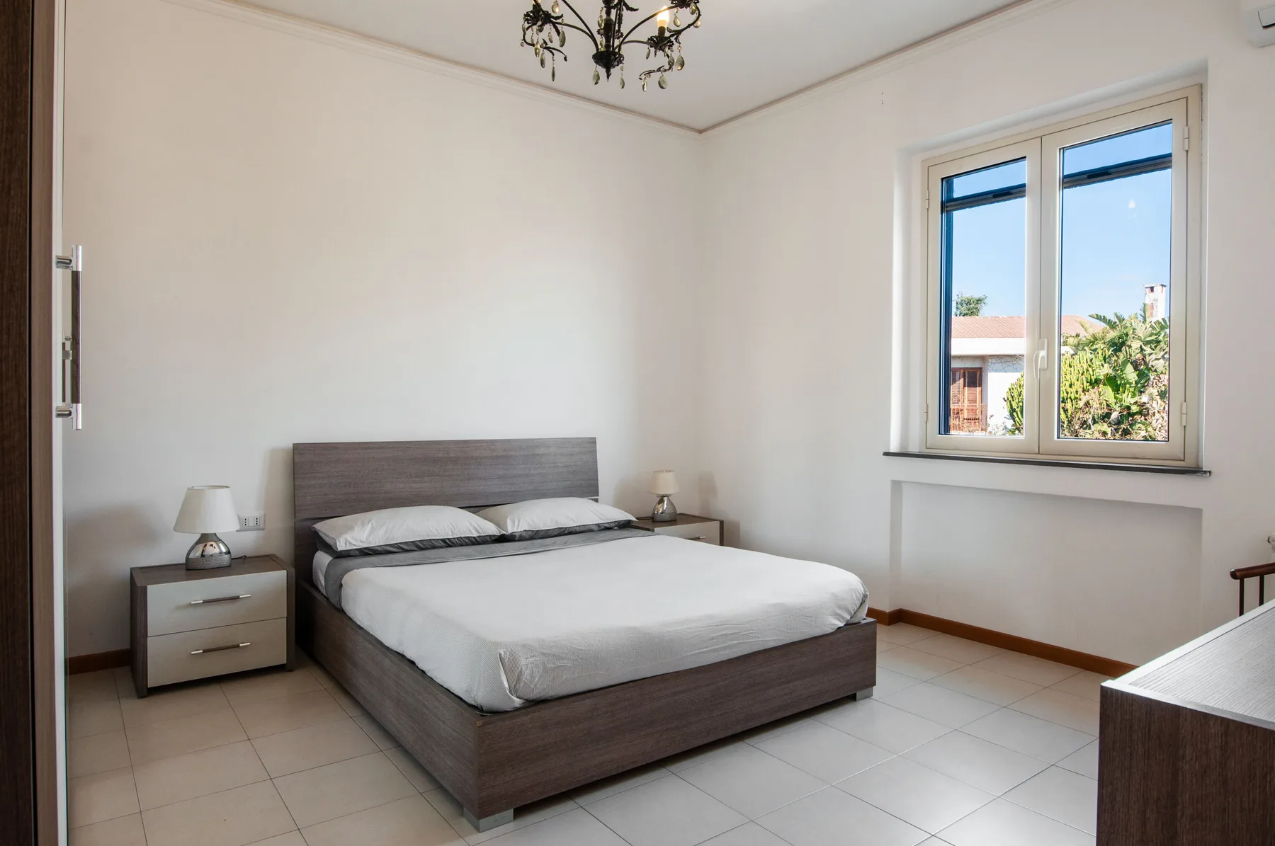 A bedroom with a double bed and a large window.