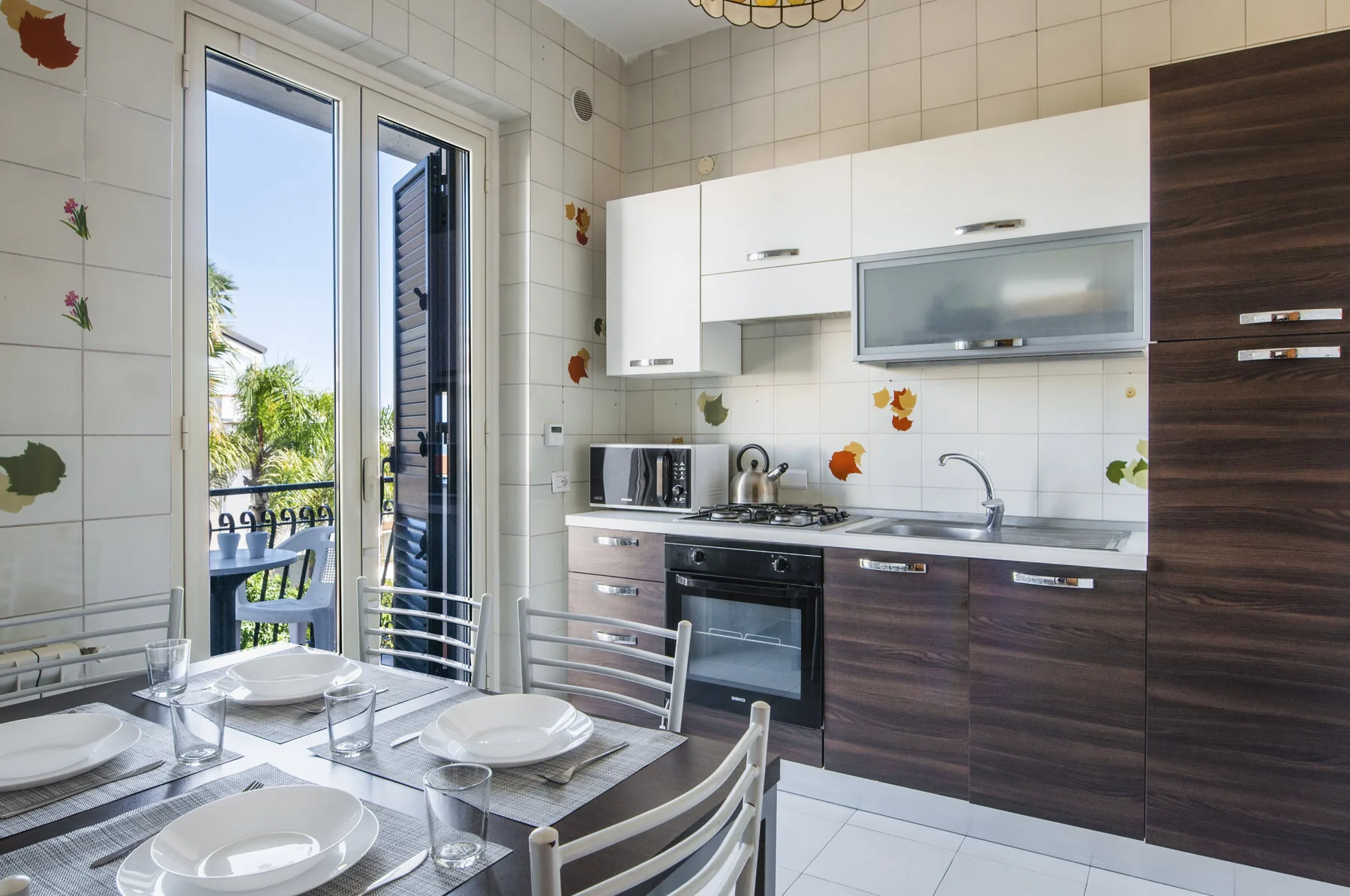 A bright kitchen and dining area with a table set beside glass doors.