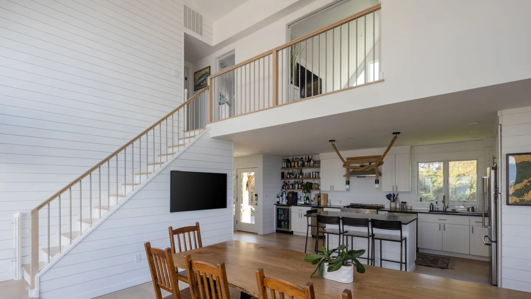 Una sala de estar y cocina de concepto abierto con una escalera y una mesa de comedor.
