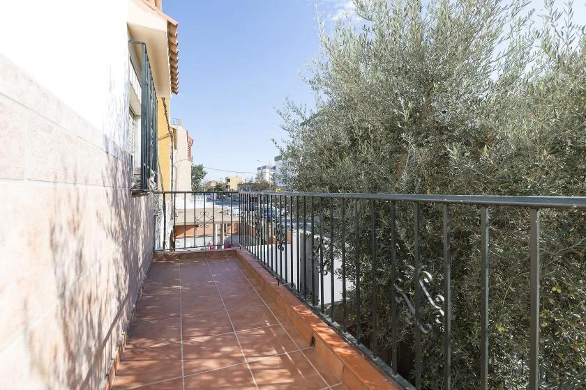 A tiled balcony overlooks leafy trees and nearby buildings.