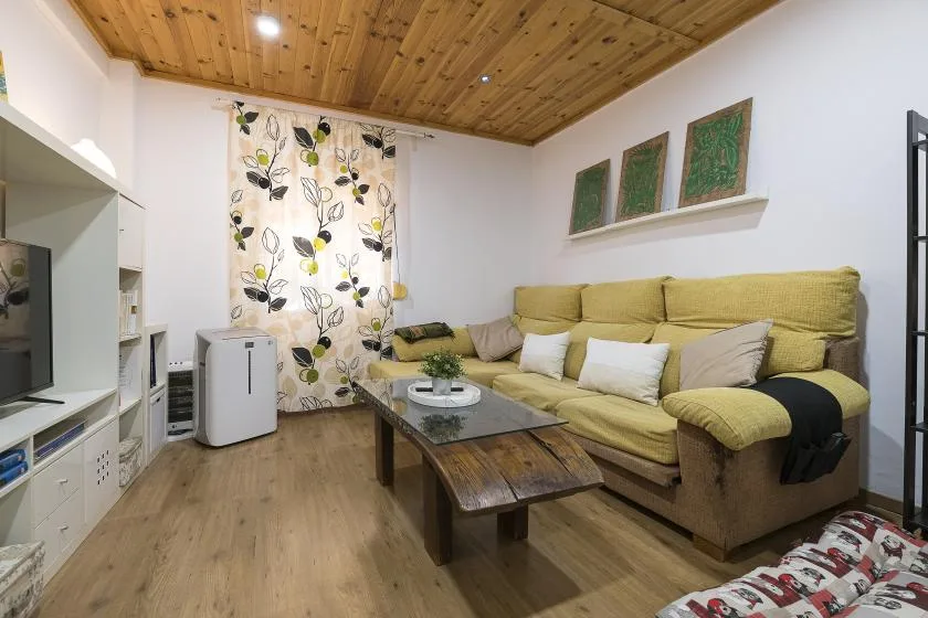 A living room with yellow seating and a wooden coffee table.