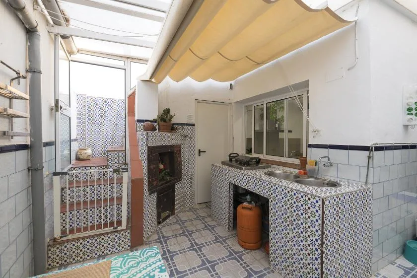 A tiled kitchen area with a counter, sink, and gas cooktop under a canopy.