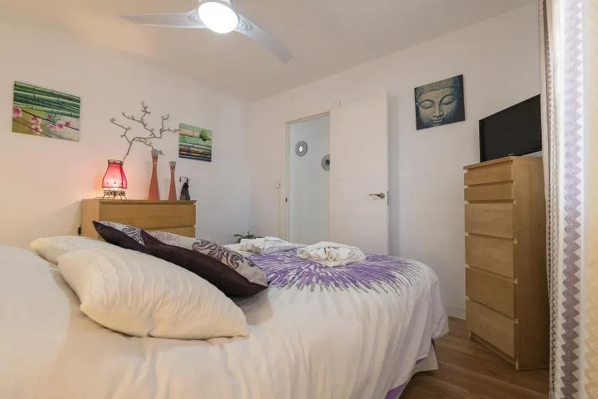 A bedroom with a bed dressed in white and purple bedding.