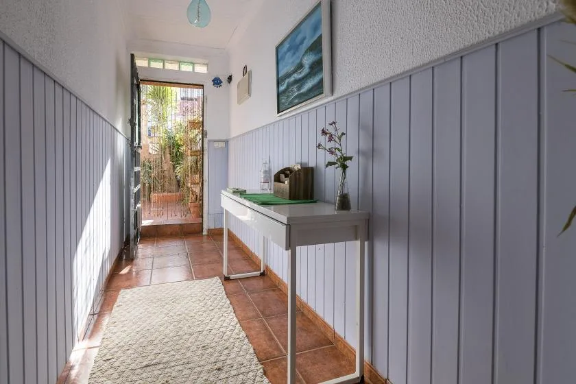 A narrow entry hallway has a console table and a glazed door opening onto greenery.