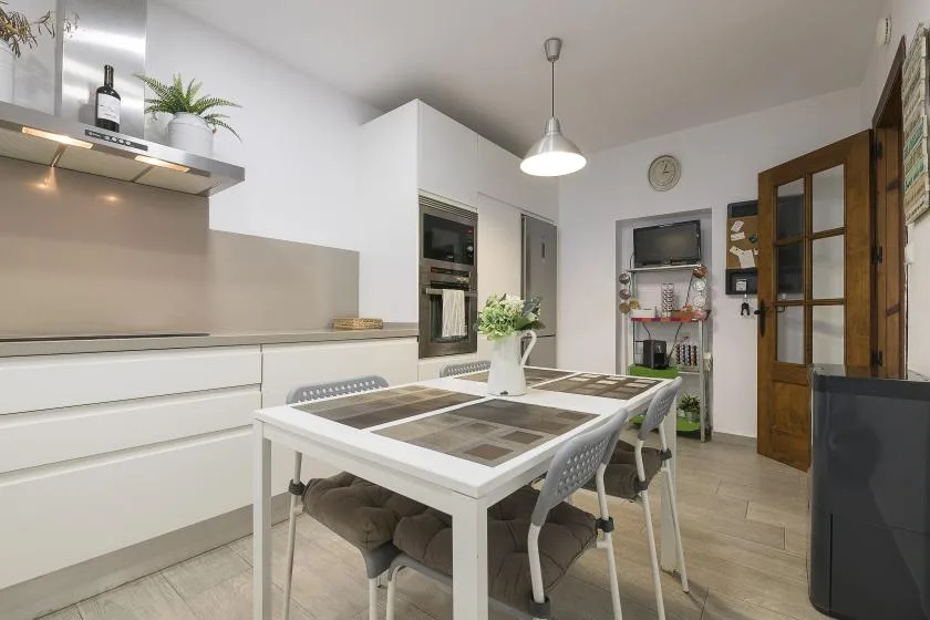 A bright kitchen with a dining table and chairs beside the cabinets.