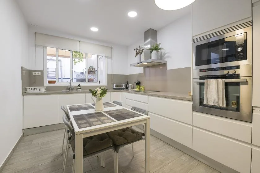 A bright modern kitchen with a dining table and built-in appliances.