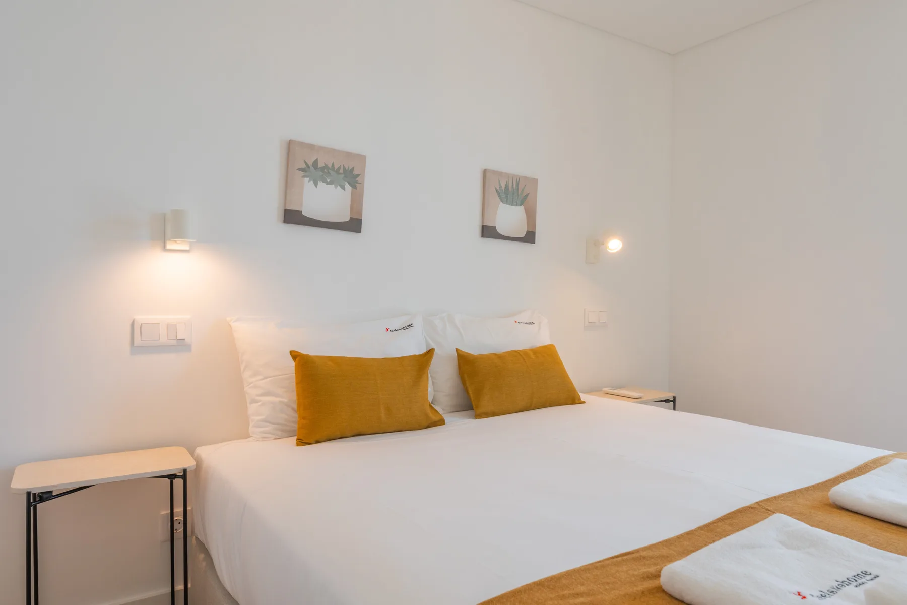 Un dormitorio con una cama bien tendida y cojines decorativos color mostaza.
