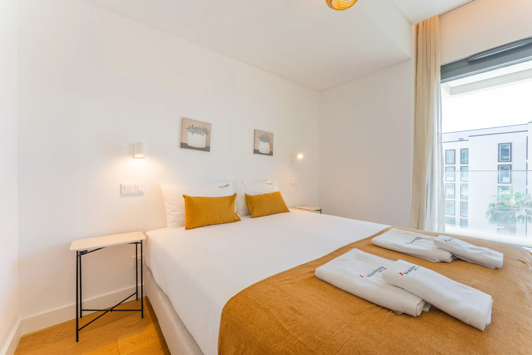 Un dormitorio luminoso con una cama bien hecha y una ventana grande.