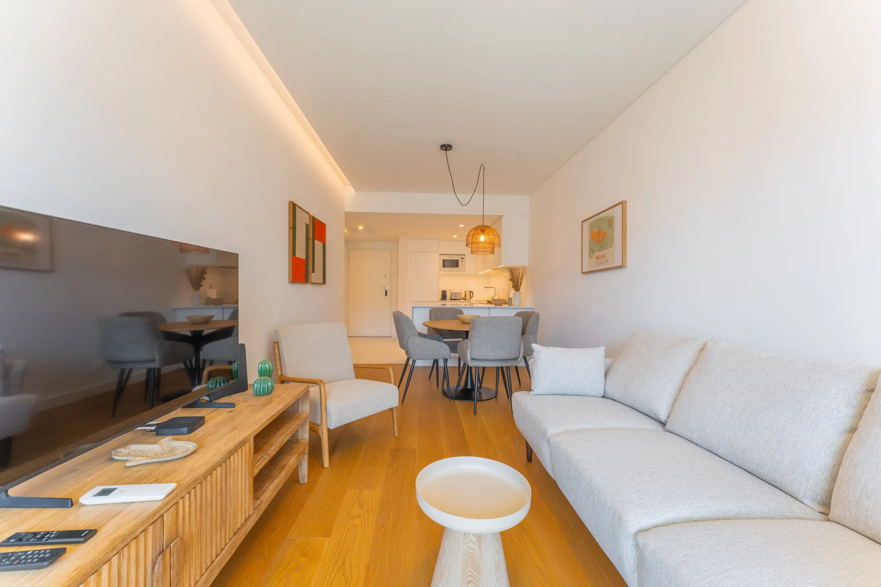 Sala de estar con sofá, televisor y comedor al fondo.