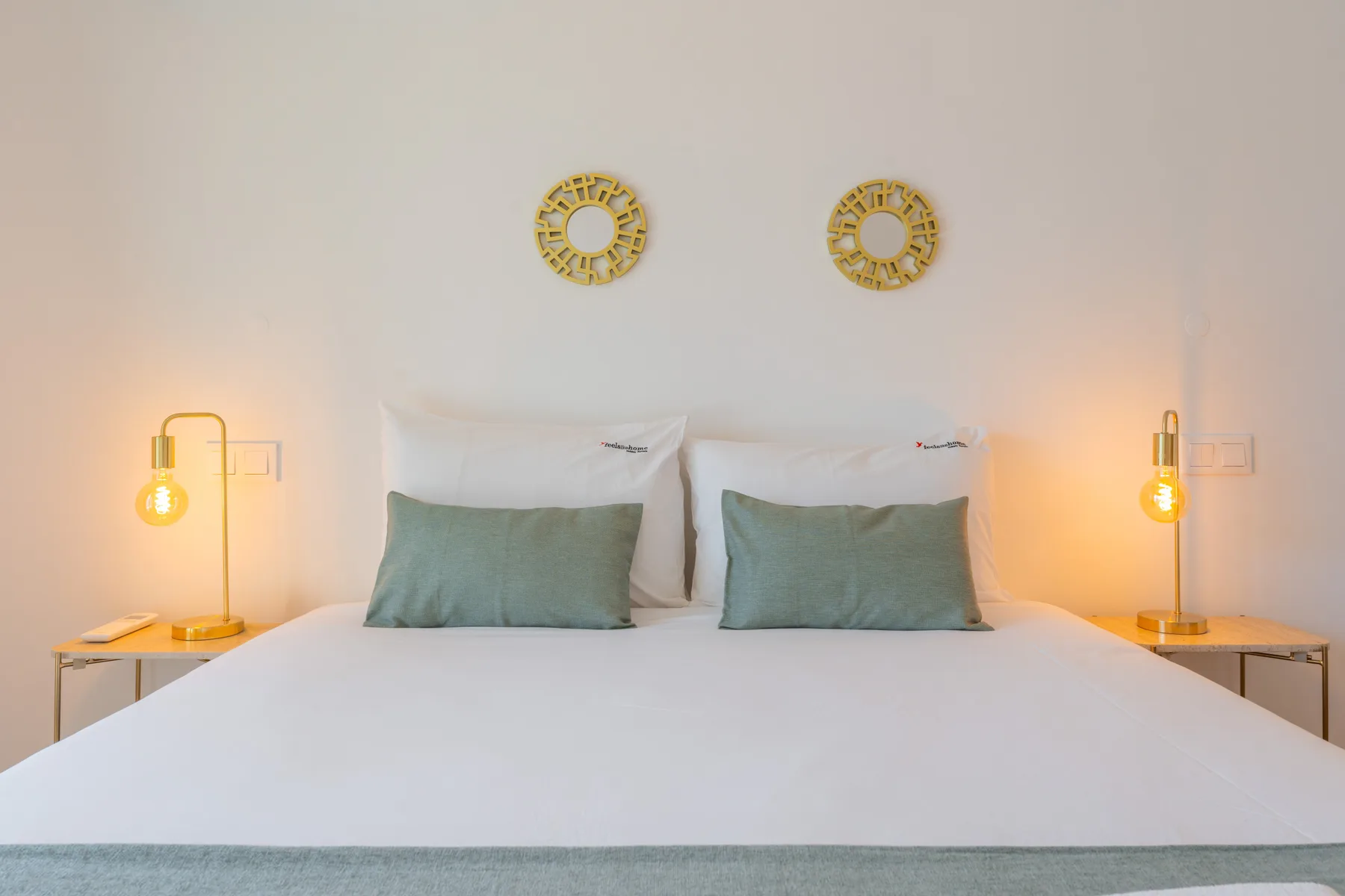 Un dormitorio con una cama bien hecha y lámparas de mesilla a juego.
