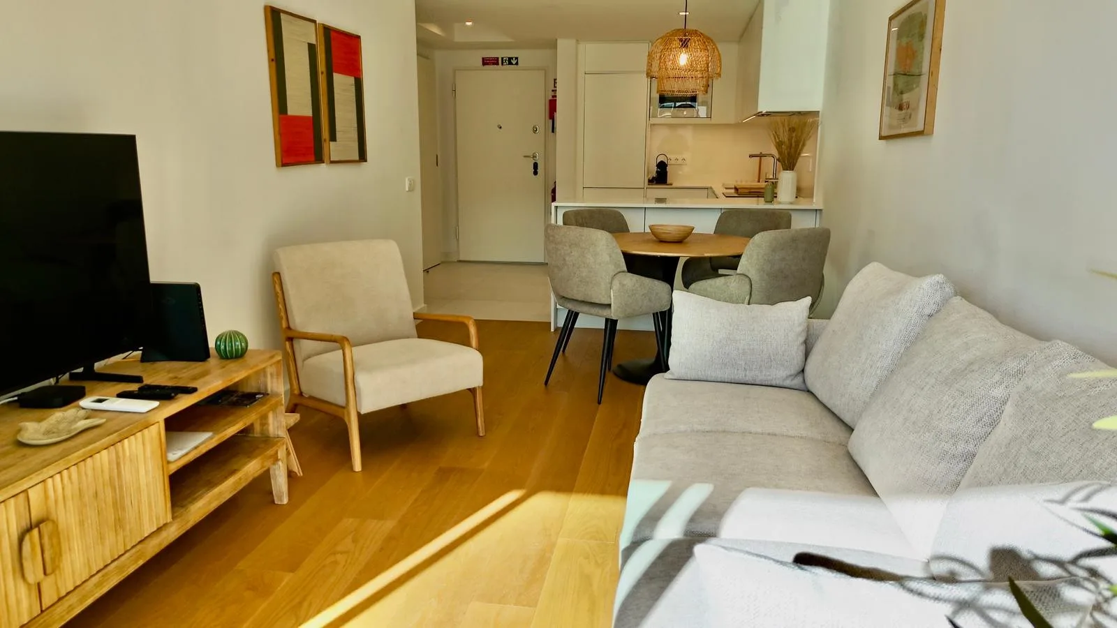 Sala de estar y comedor con asientos, un televisor y una cocina abierta.