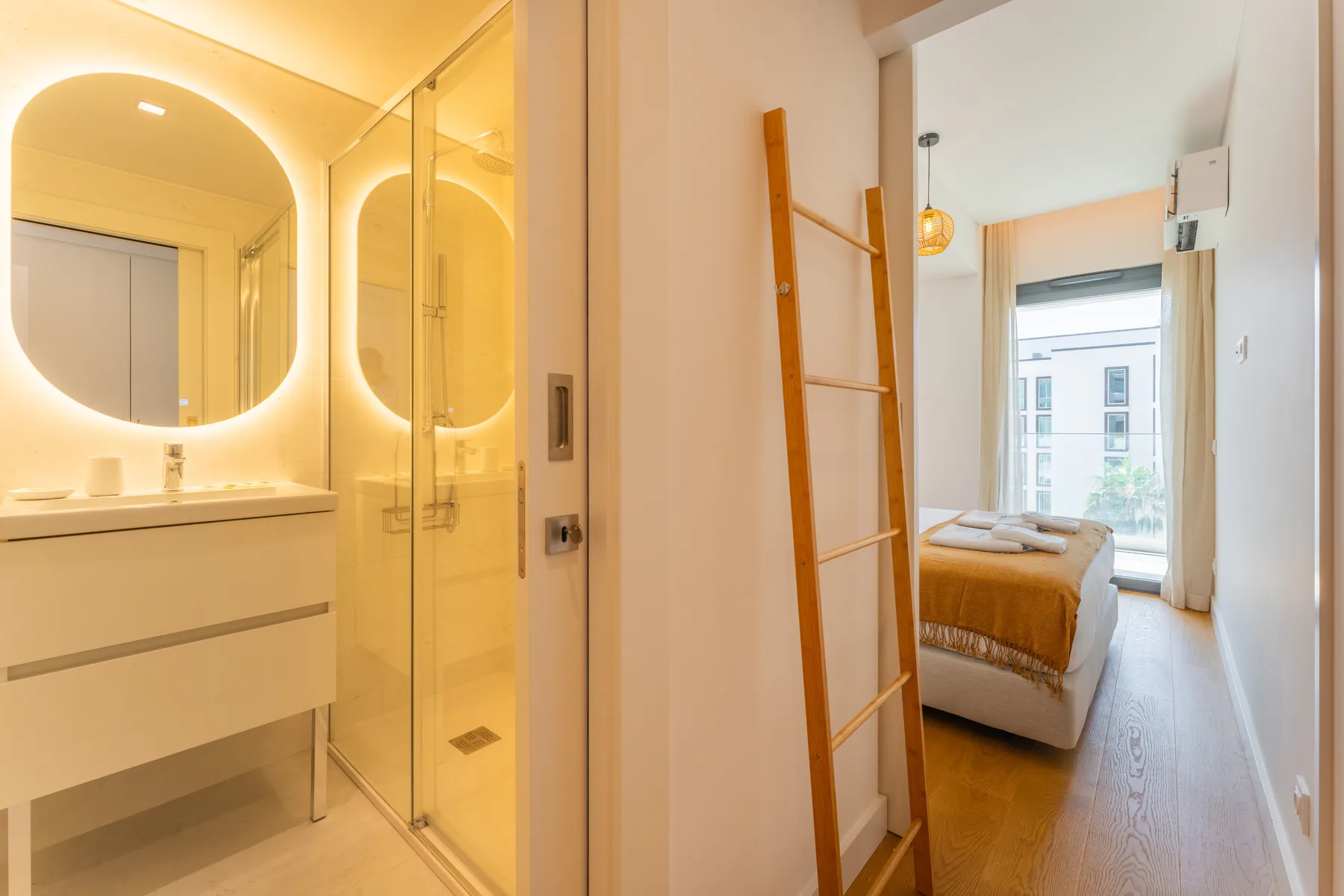 Un dormitorio luminoso se ve a través de una puerta abierta junto a un lavabo.