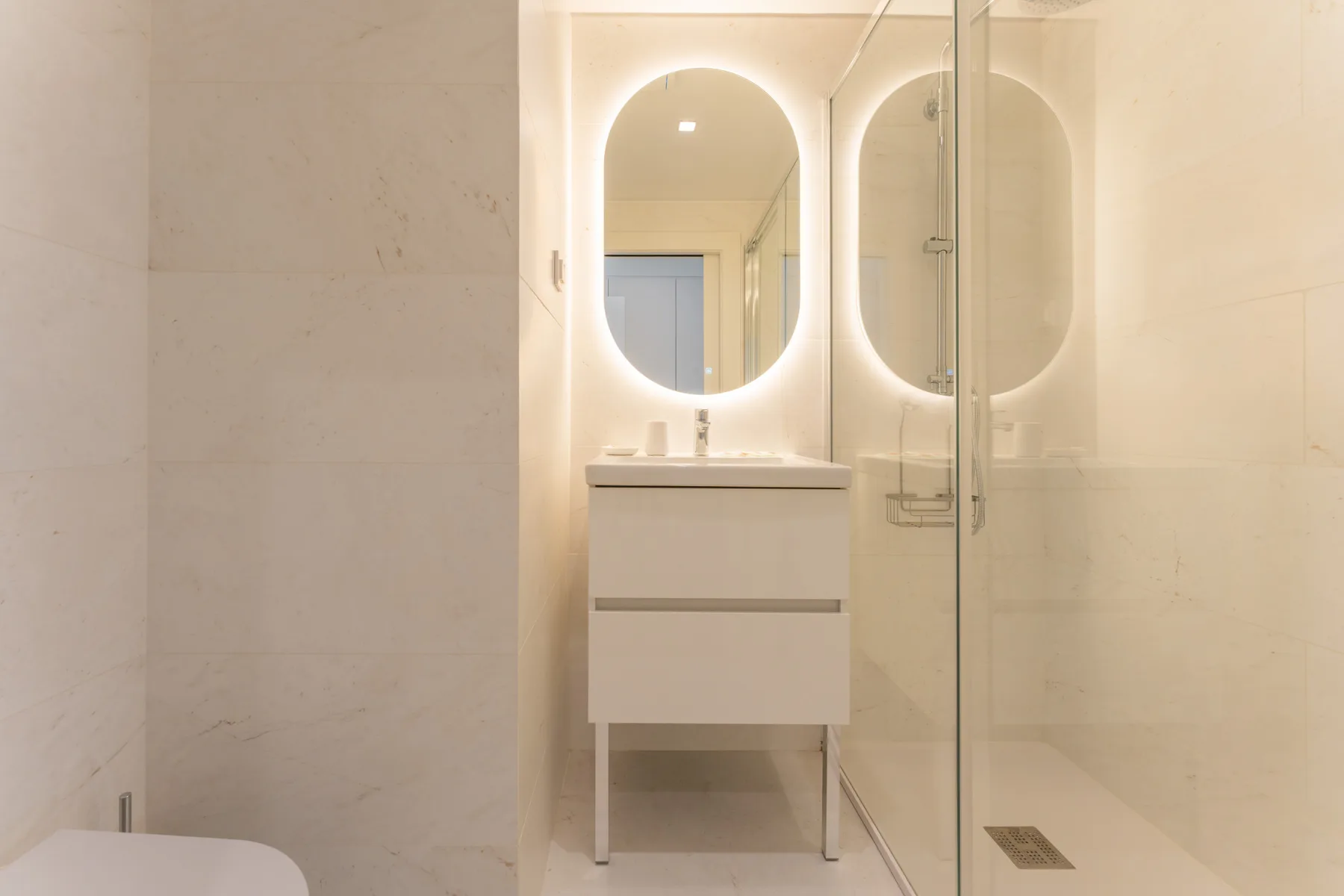 Un baño luminoso con lavabo y ducha de cristal.