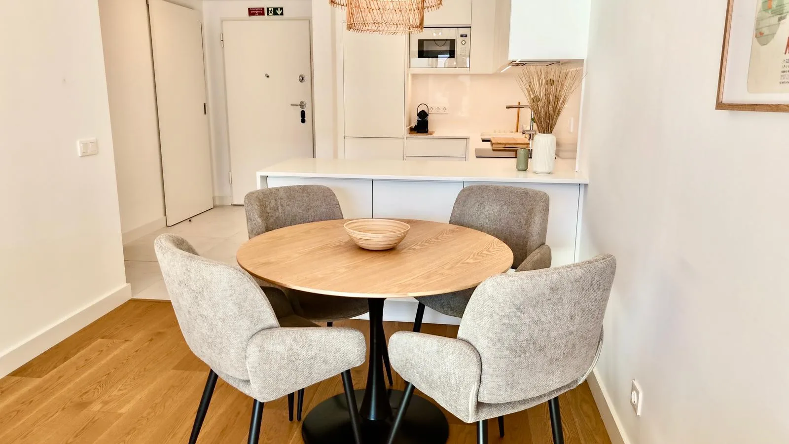Comedor con una mesa redonda de madera y sillas junto a una cocina compacta.
