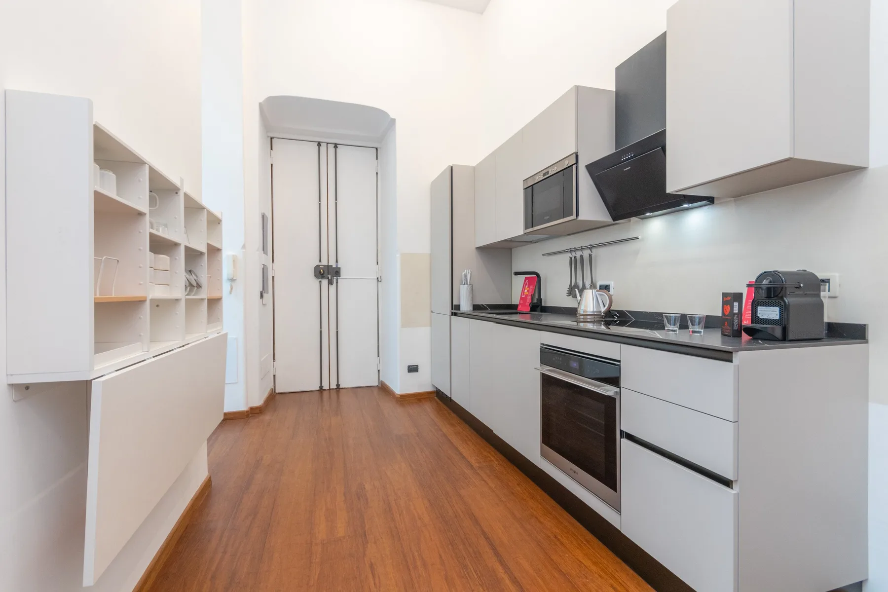 A modern kitchen with white cabinets and a wood floor.