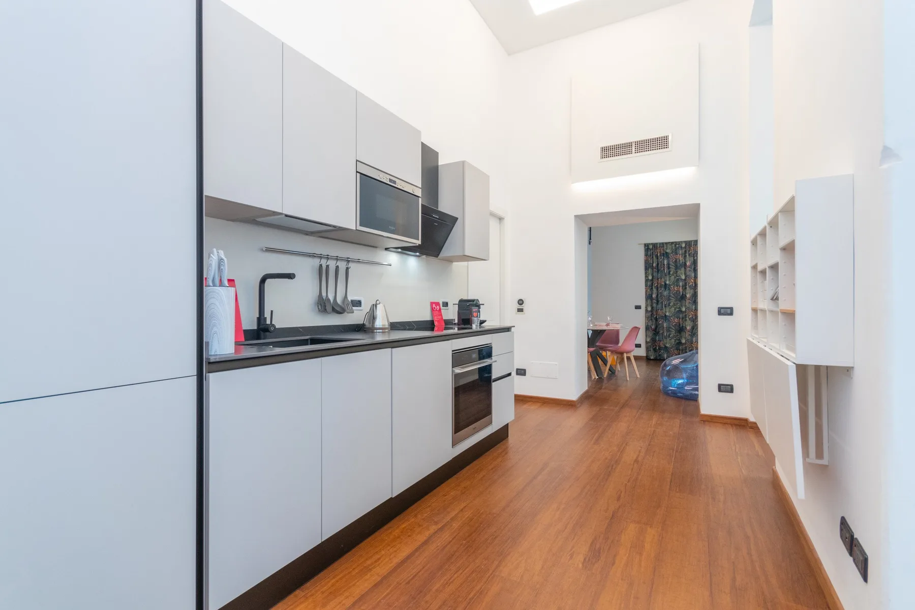 A modern kitchen with white cabinets and a wooden floor.