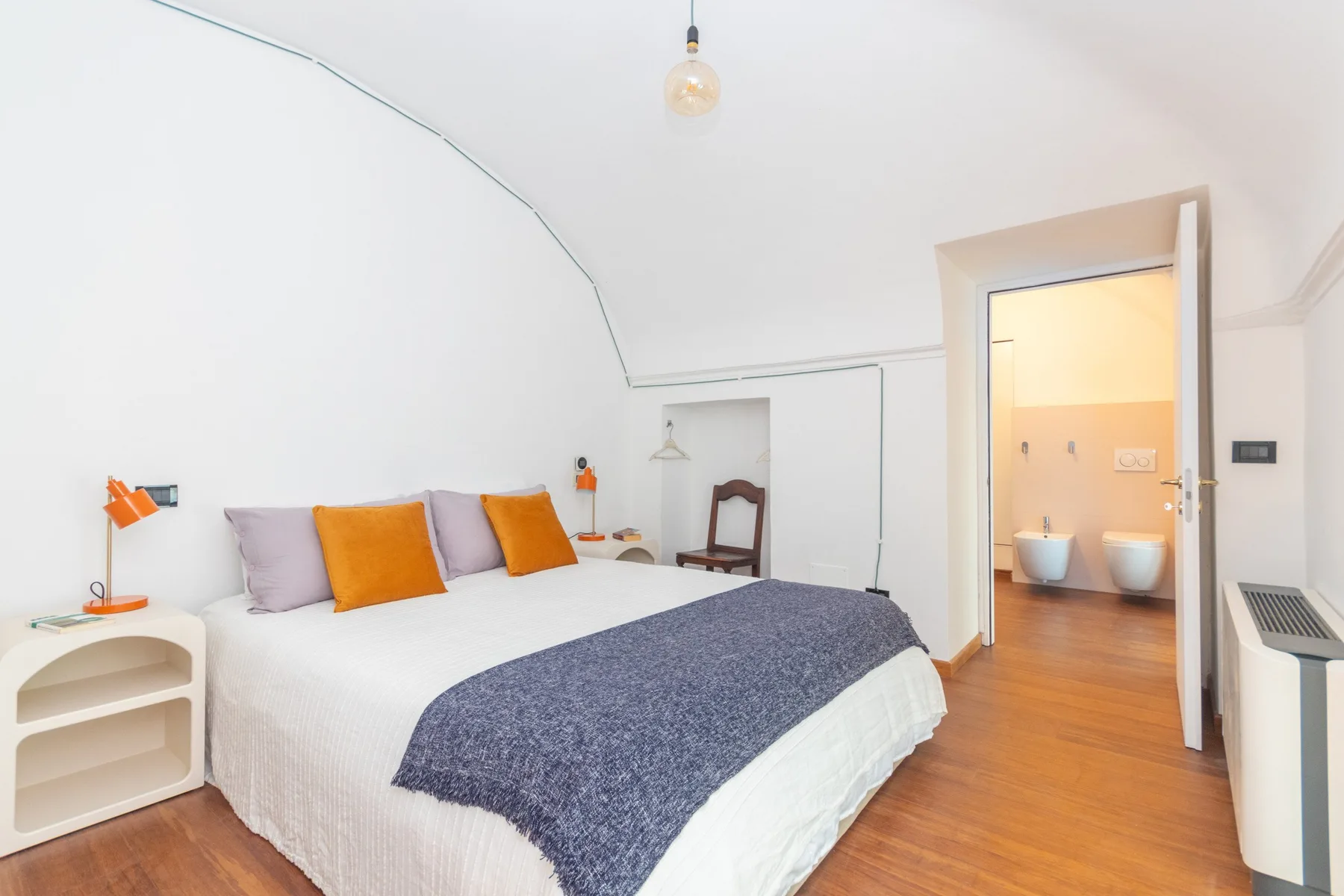 Un dormitorio luminoso con una cama grande y una puerta abierta al baño.