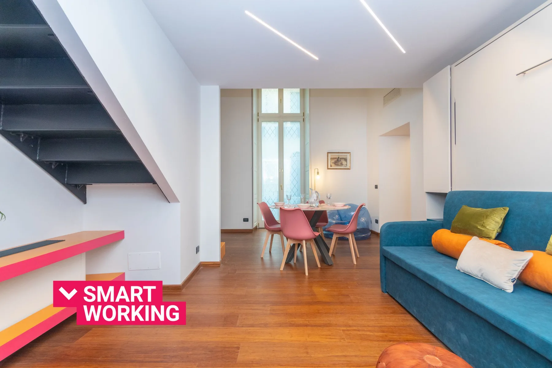 Una sala de estar y comedor moderna, con un sofá azul y una mesa junto a la ventana.