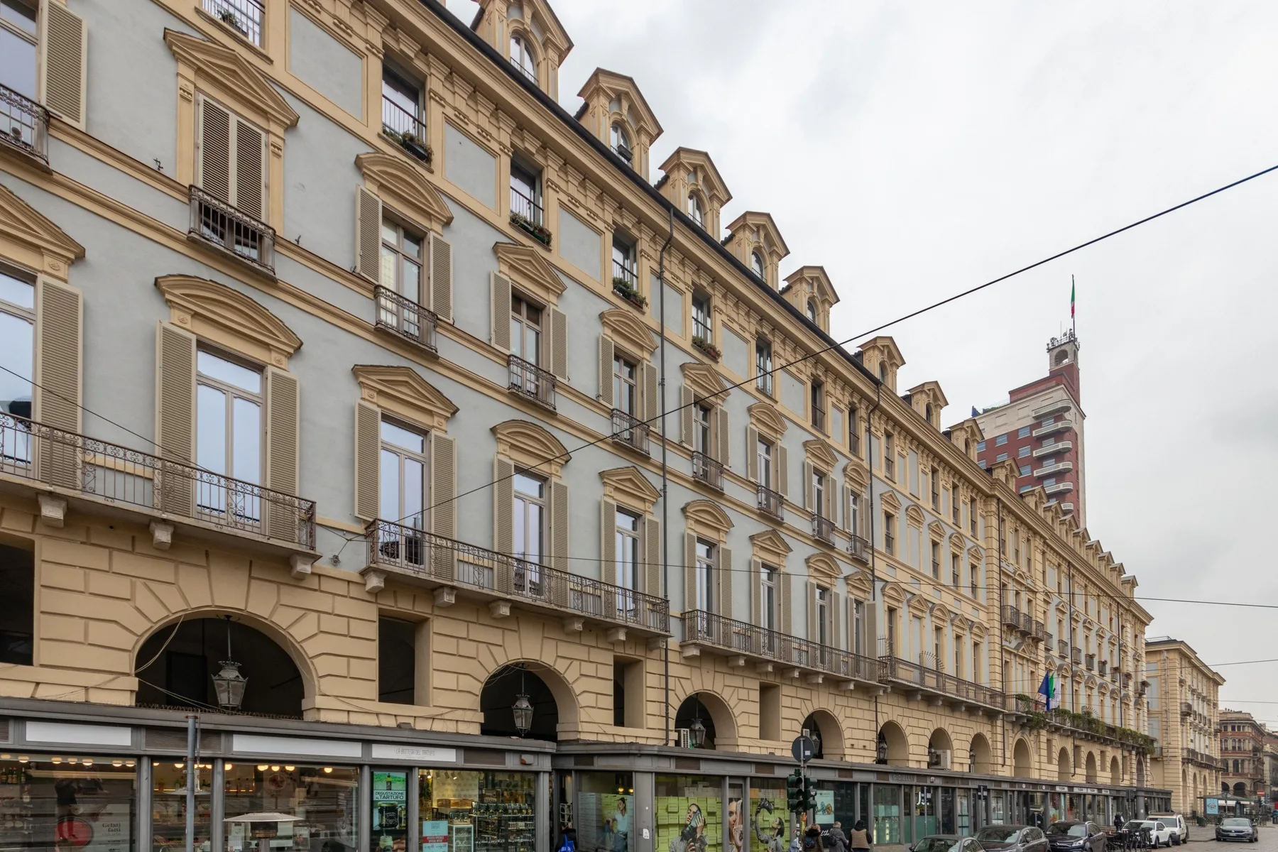 A long multistory building with rows of windows and shops along the street.