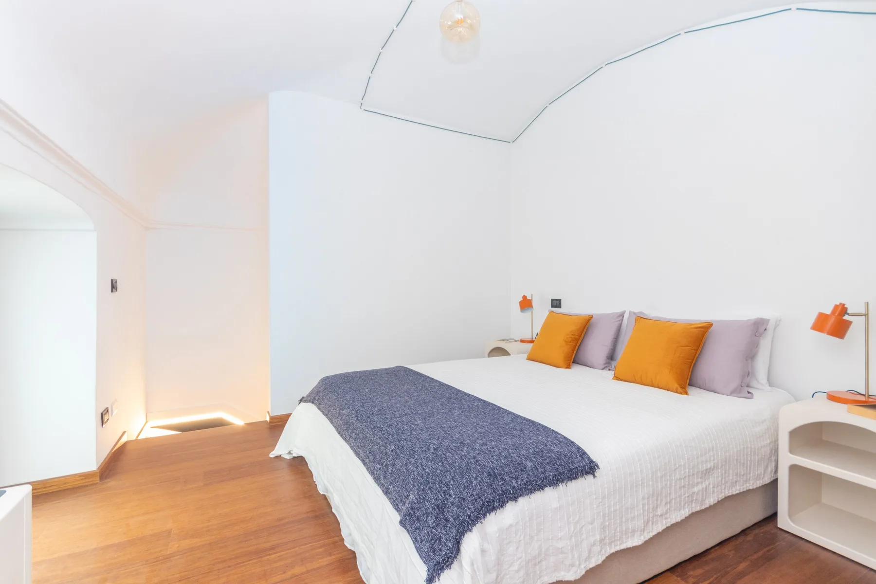 Un dormitorio luminoso con una cama grande y una manta azul oscuro.