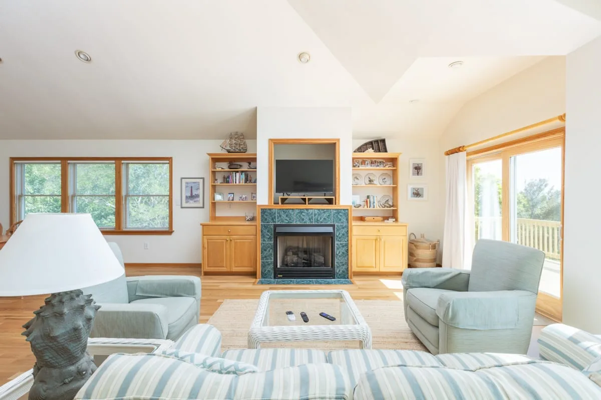 A bright living room with seating, a fireplace, and large windows.