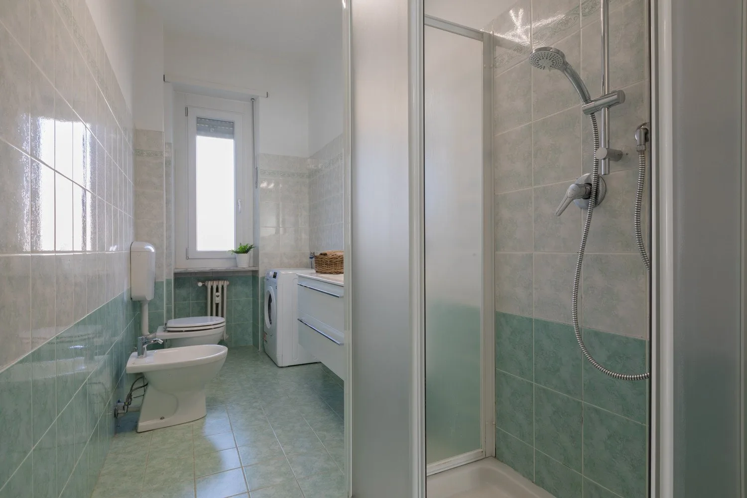 A tiled bathroom with a toilet, sink, and shower.
