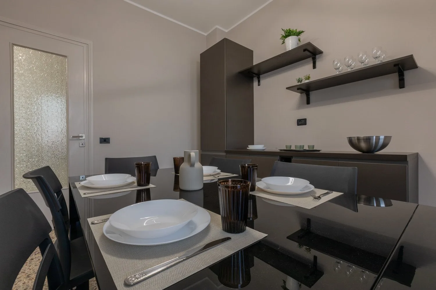 A dining area with a set table and dark cabinetry along the wall.