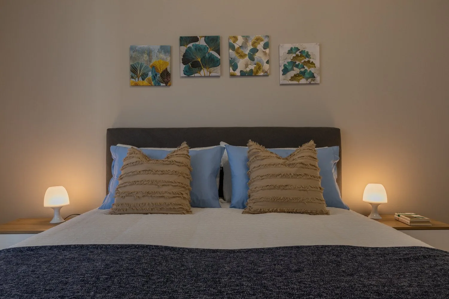Bedroom with a neatly made bed and floral artwork above the headboard.