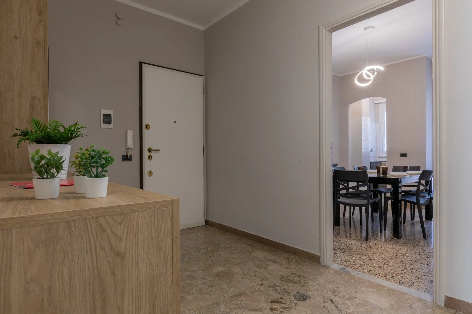 An entry hall opens onto a dining area with a table and chairs.