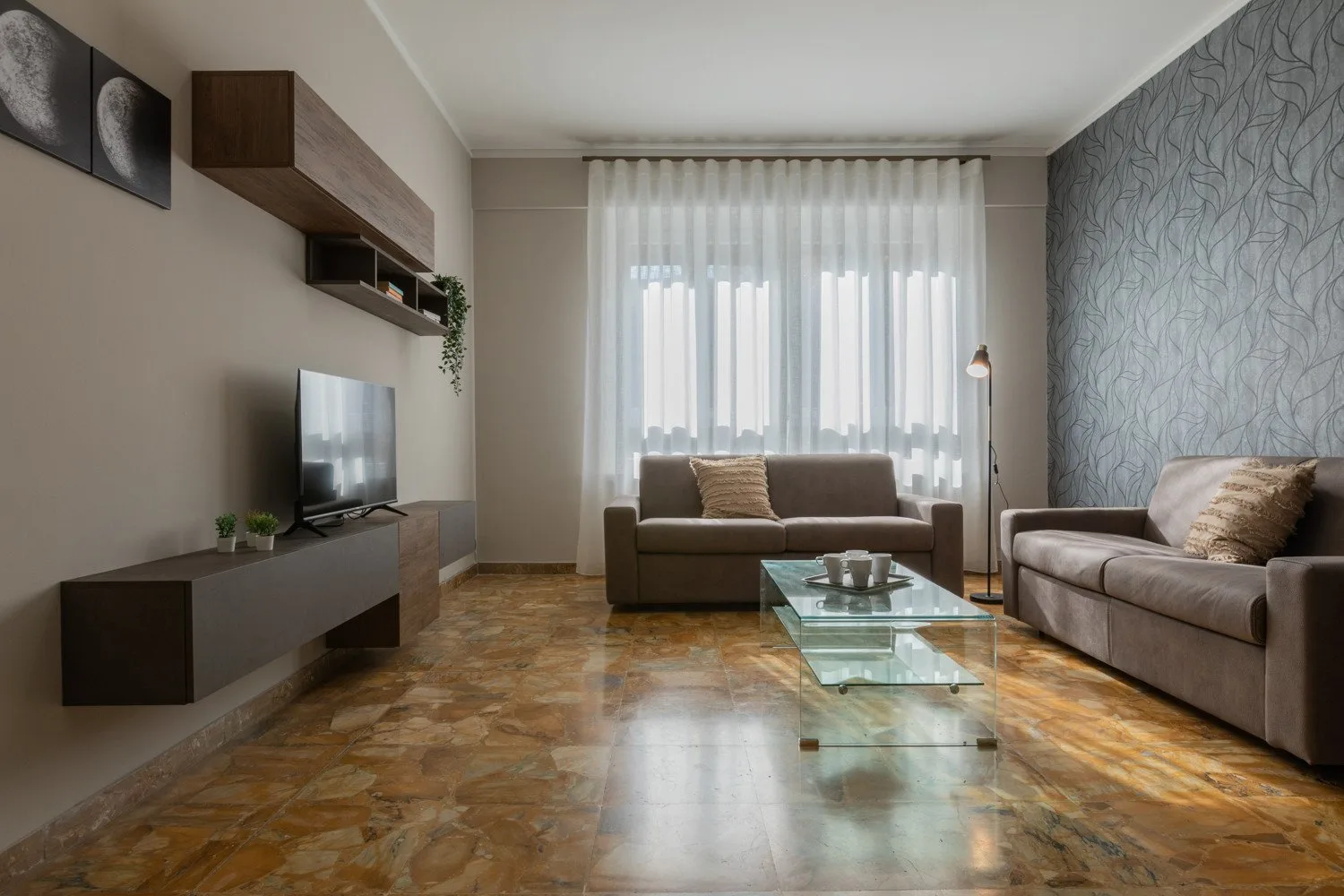 A living room with seating, a television, and a glass coffee table.