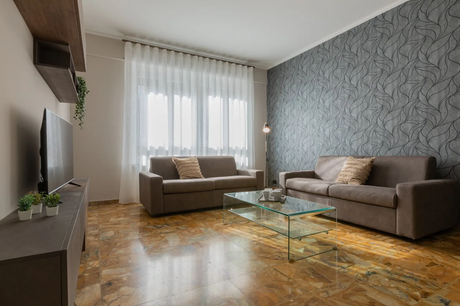 A living room with two seating areas and a glass coffee table.