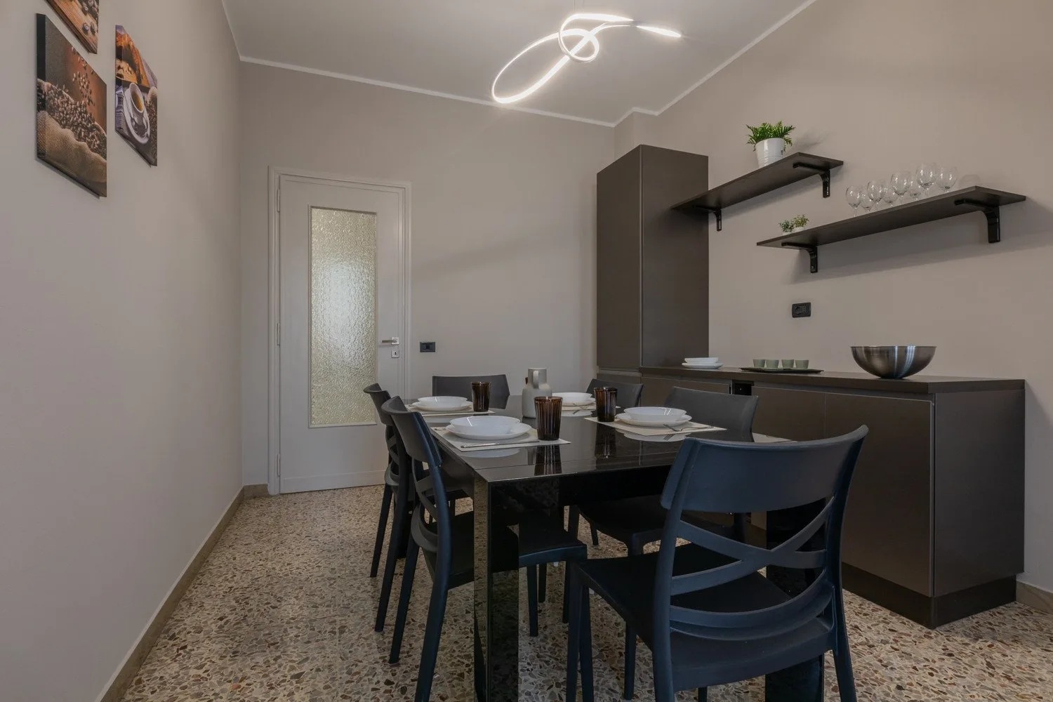 A dining room with a set table and dark chairs beside a cabinet.