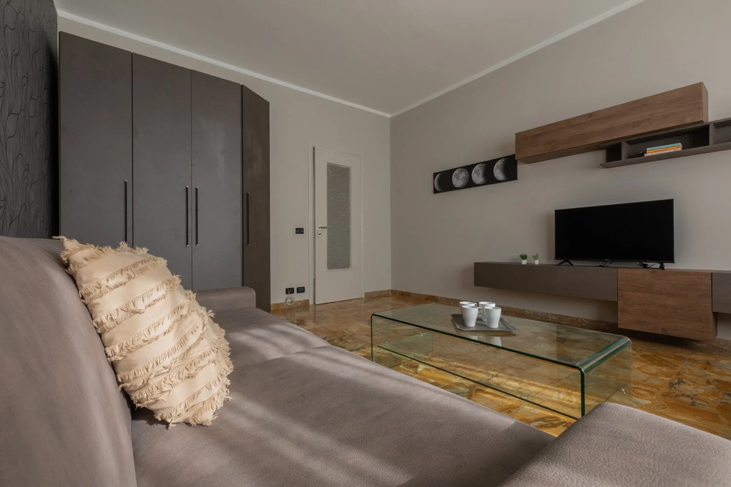 A living room with seating, a television, and a glass coffee table.