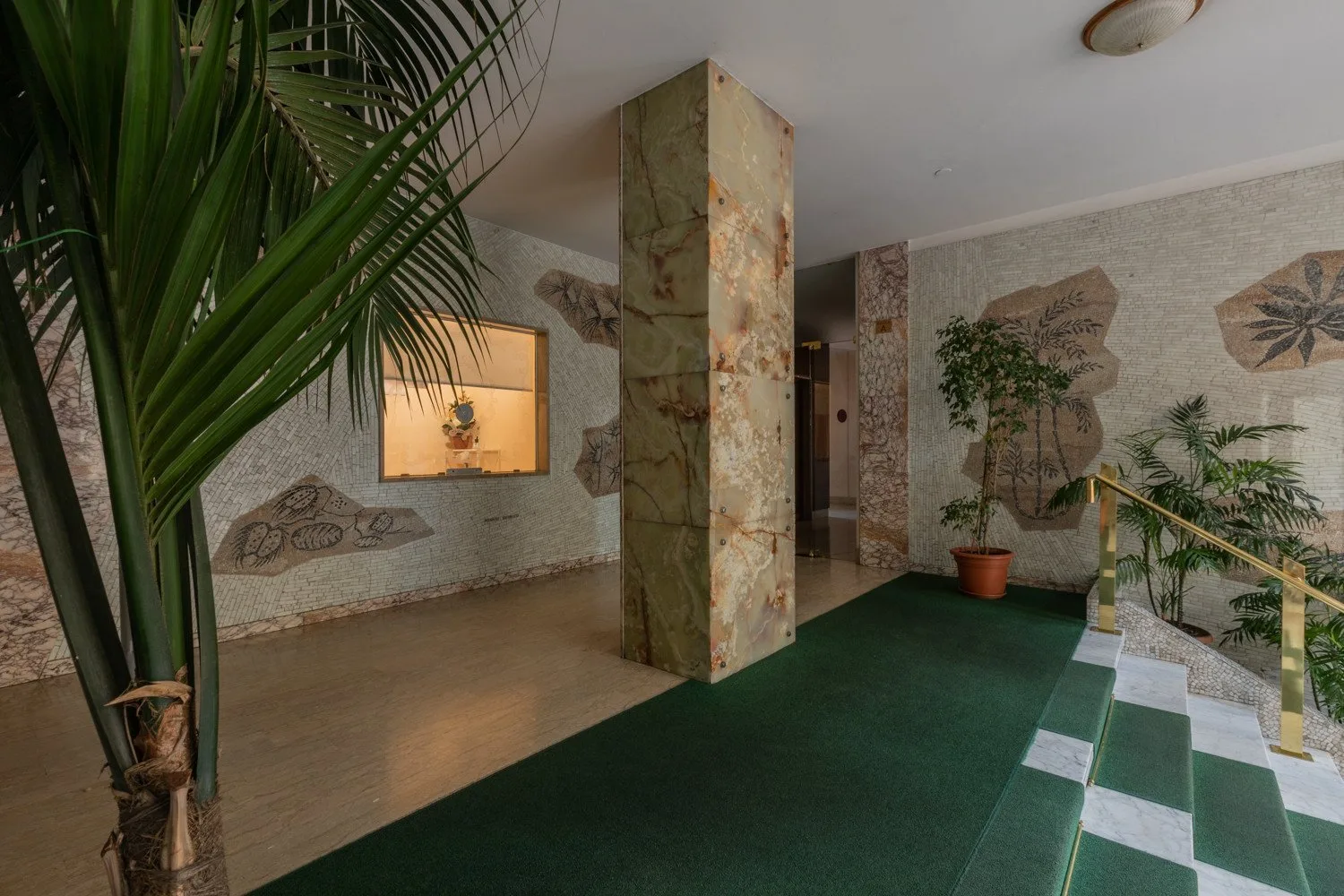 An indoor entryway with a green floor runner and decorative wall panels.