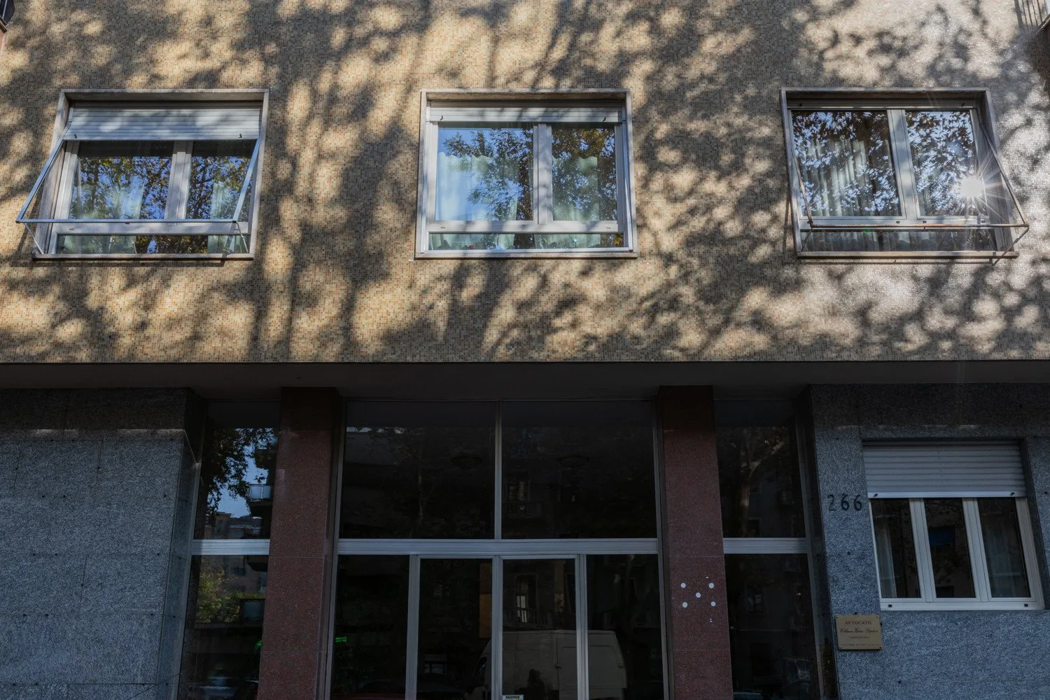 Building facade with several windows and a glass entrance below.