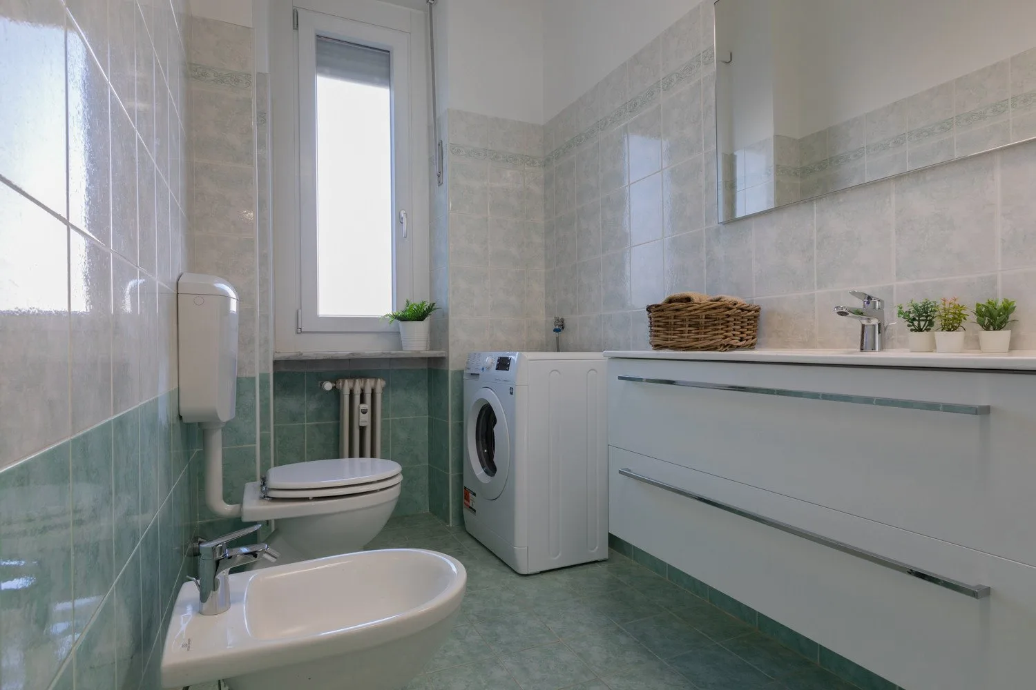 A tiled bathroom with a bathtub, toilet, and washing machine.