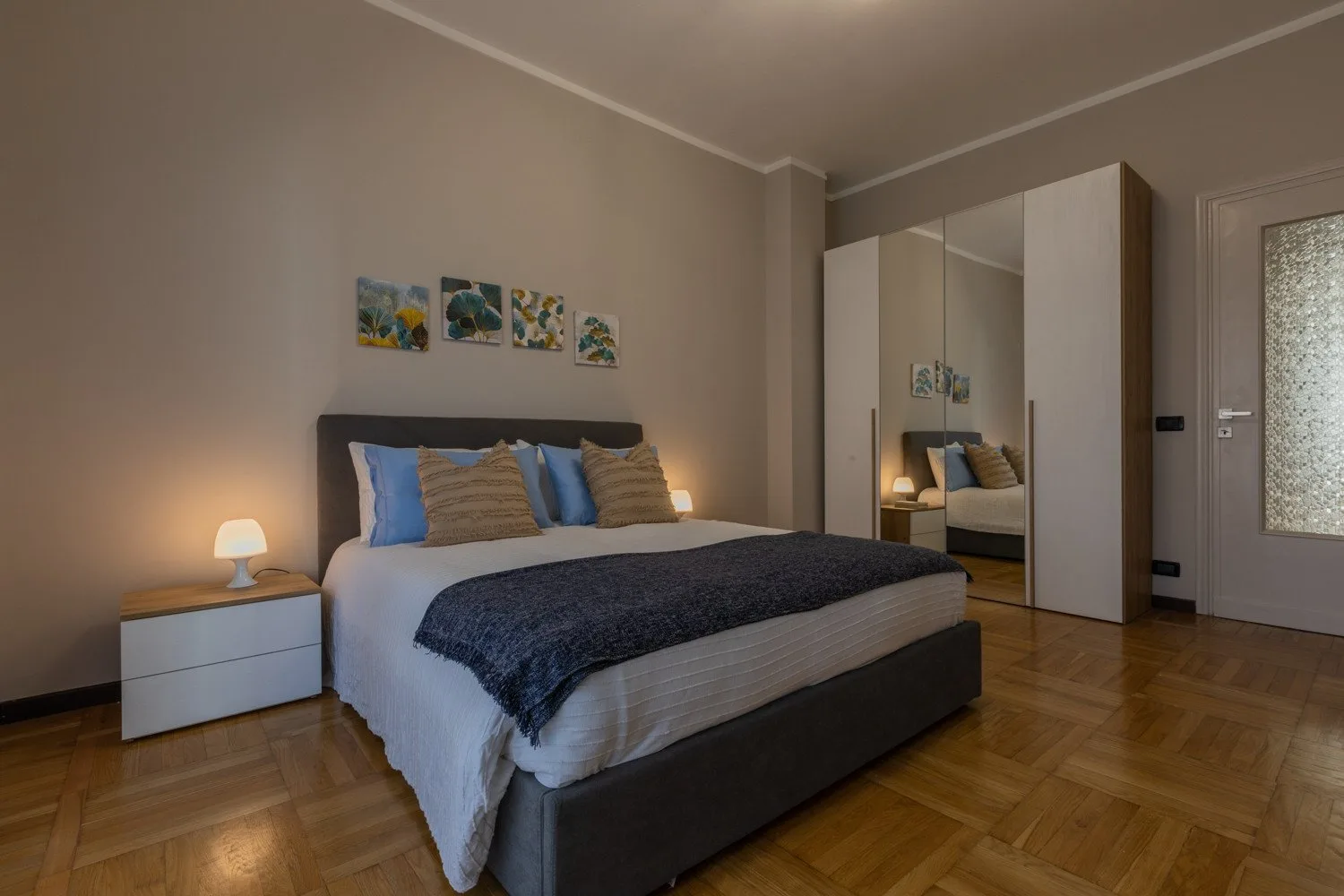 A bedroom with a neatly made bed and mirrored wardrobe.