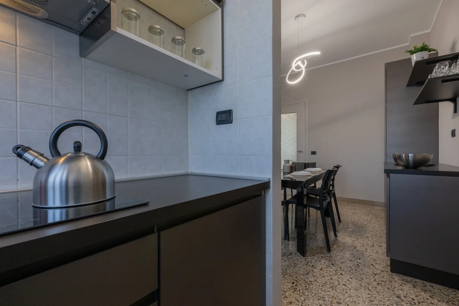 A compact kitchen opens onto a dining area with a table and chairs.