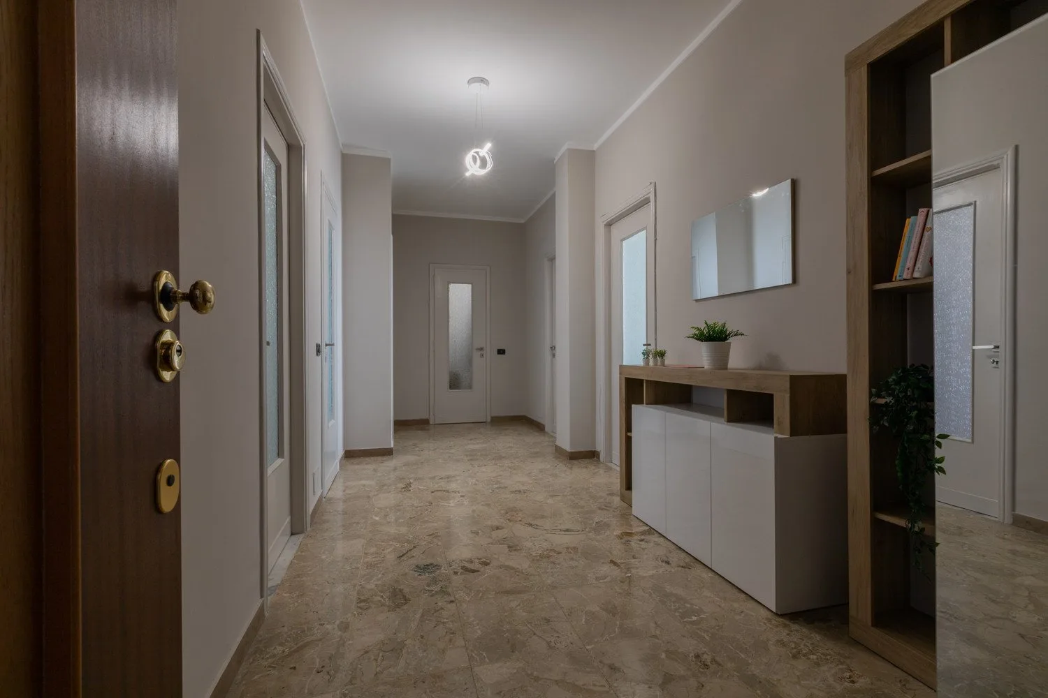 A bright hallway with several doors and a low cabinet along the wall.