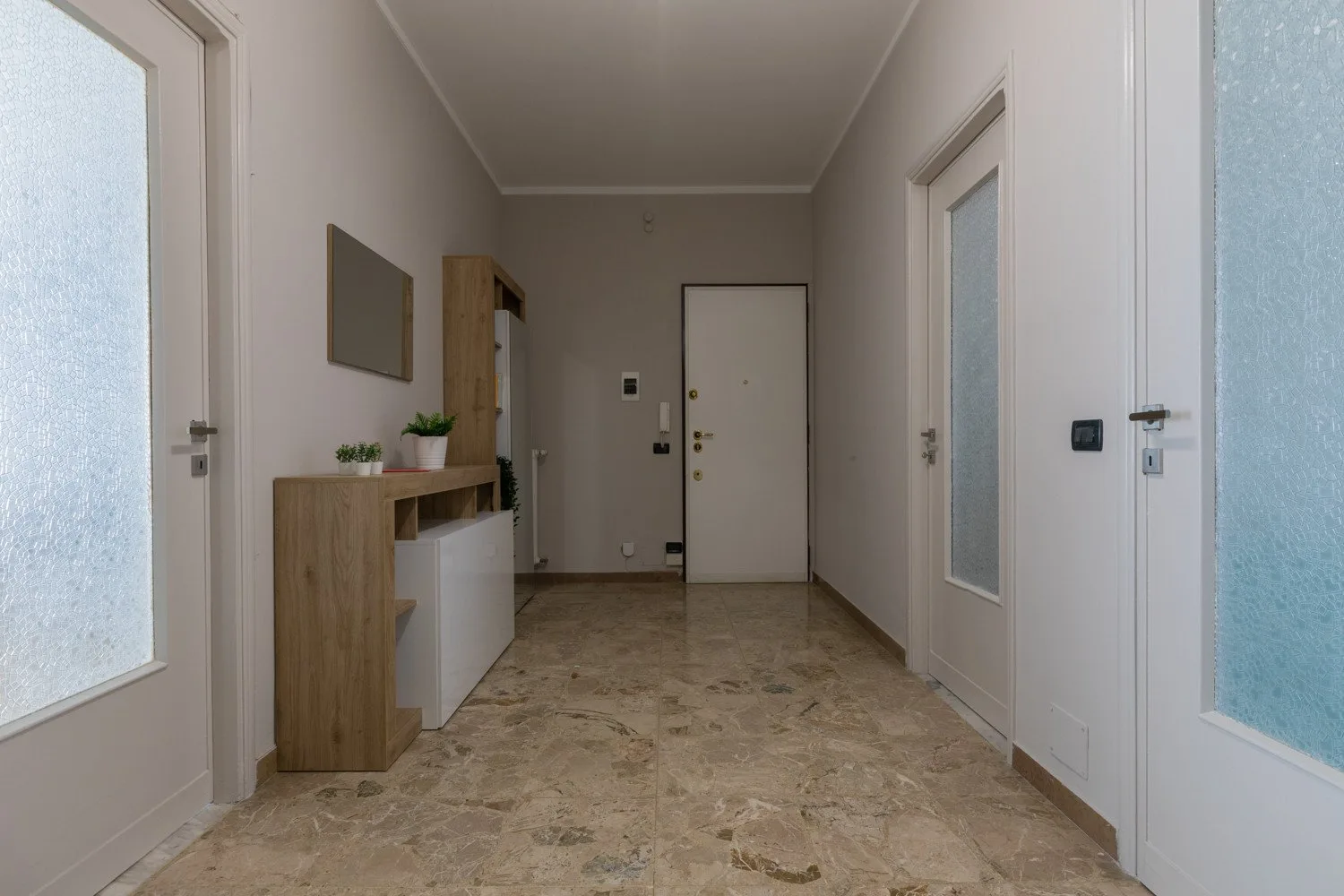 A narrow entry hall with a console cabinet and several doors.