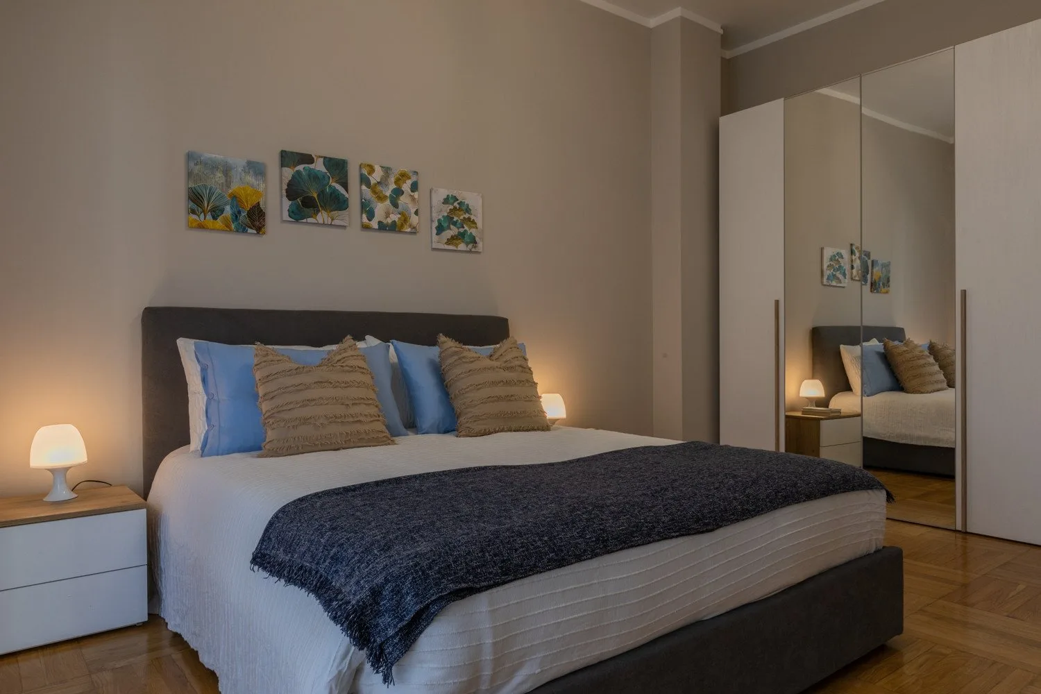 A bedroom with a made bed, decorative pillows, and mirrored closet doors.