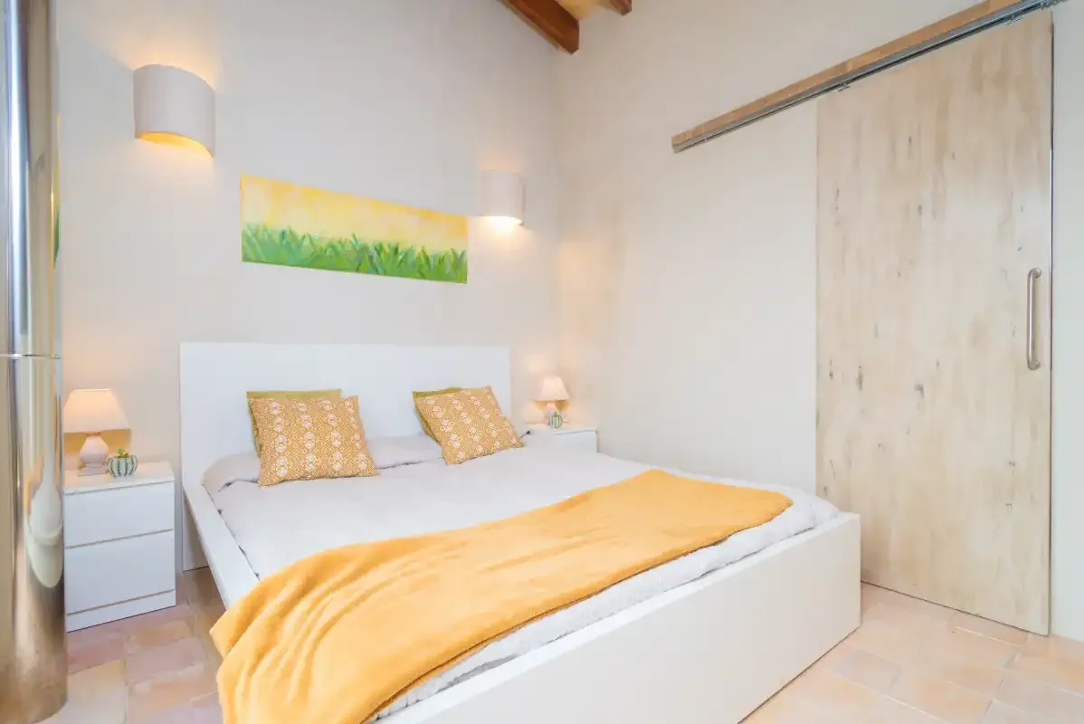 Un dormitorio con una cama bien hecha y una manta amarilla.