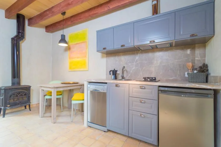 Una cocina con gabinetes azules, una encimera y una pequeña mesa de comedor.