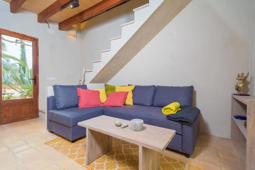 Una sala de estar con un sofá seccional azul bajo una escalera.