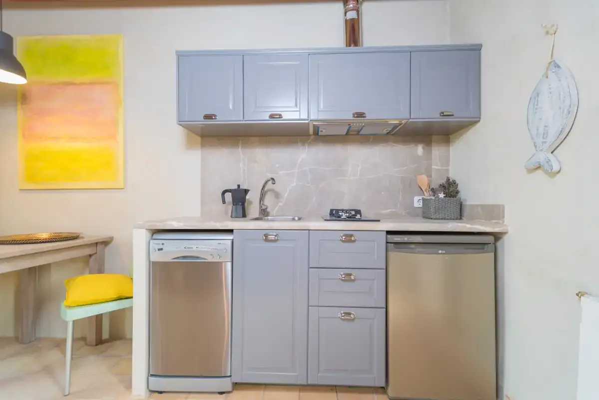Una cocina compacta con armarios azul claro y electrodomésticos de acero inoxidable.