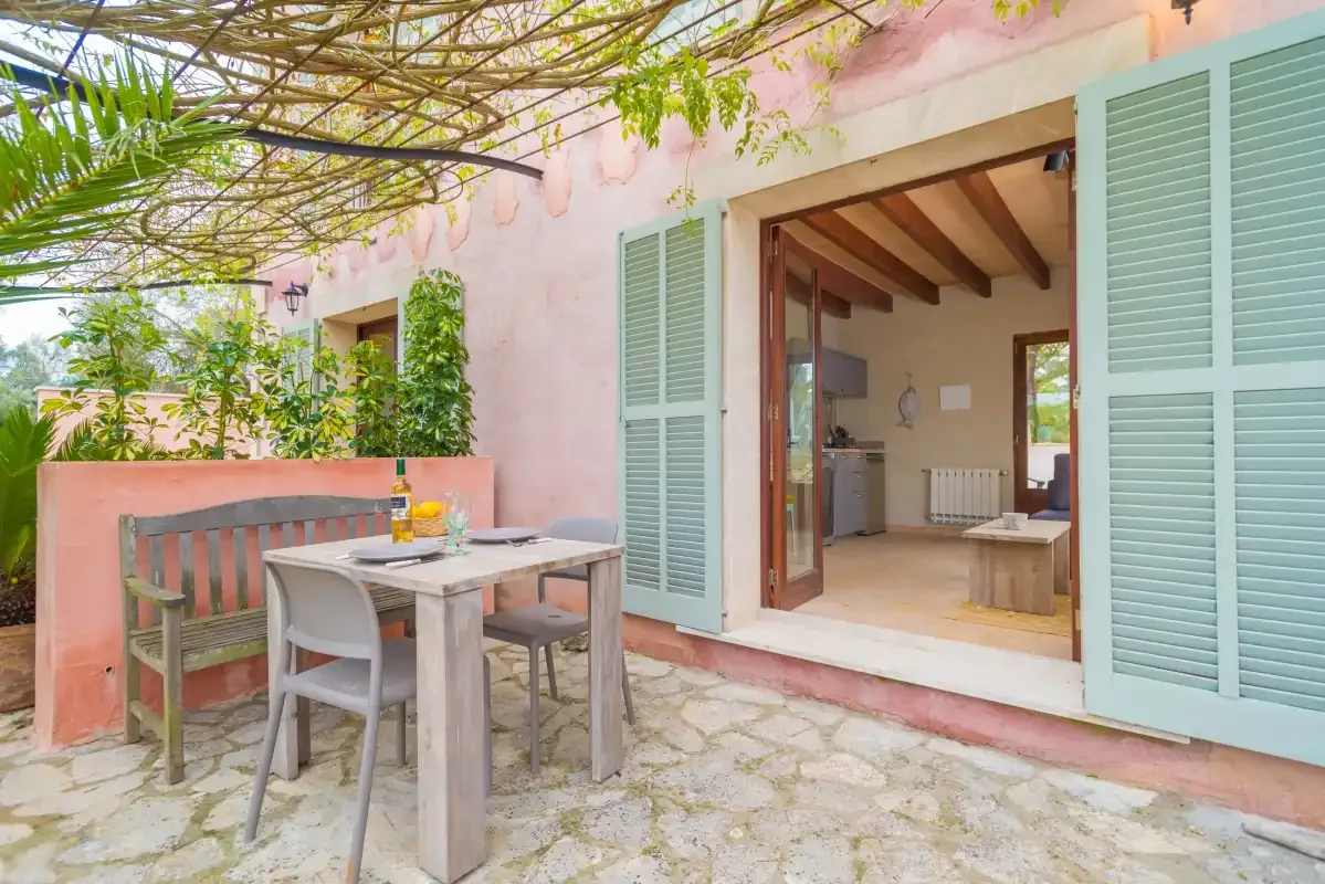Un patio cubierto con asientos al aire libre y puertas abiertas a una habitación interior.