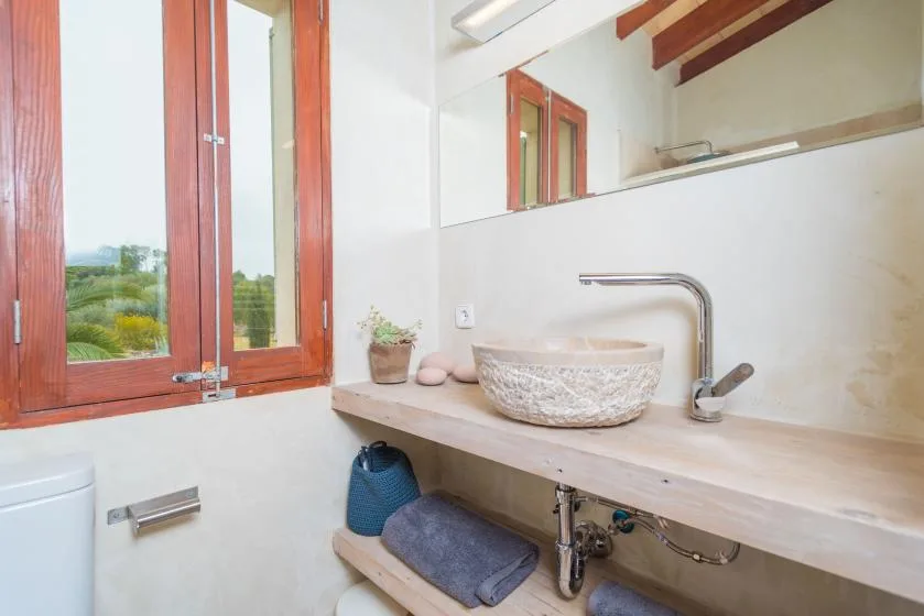 Un lavabo de baño luminoso con un lavabo sobrepuesto y un espejo grande.