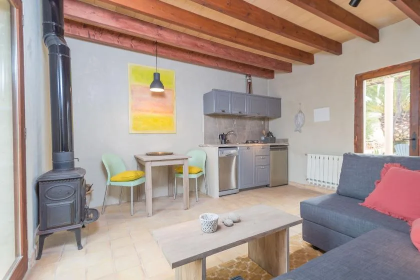 Sala de estar con mesa de comedor, cocina compacta y asientos grises.