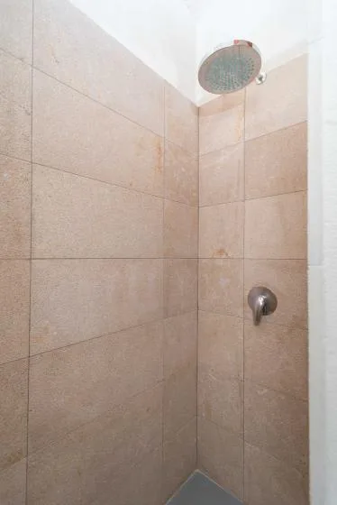 Una ducha alicatada con un cabezal de ducha redondo en alto.